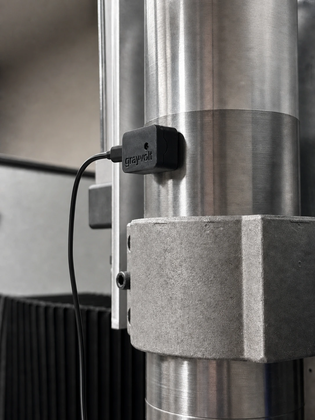 GrayVolt vibration analyzer magnetically mounted on a CNC spindle with its black USB power cable connected