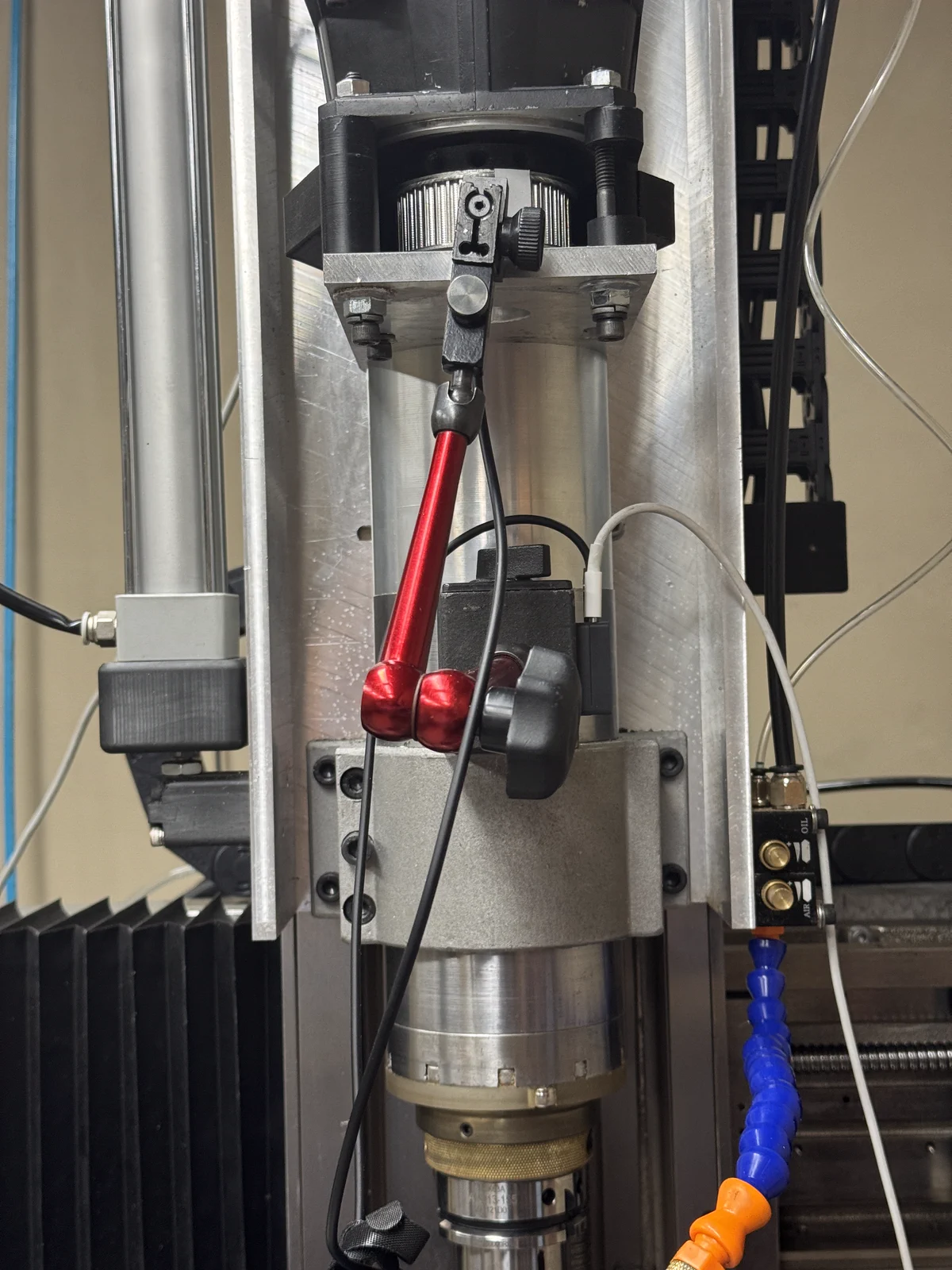 Wired GrayVolt IR tach pickup held on a red magnetic-base dial indicator stand beside a CNC spindle